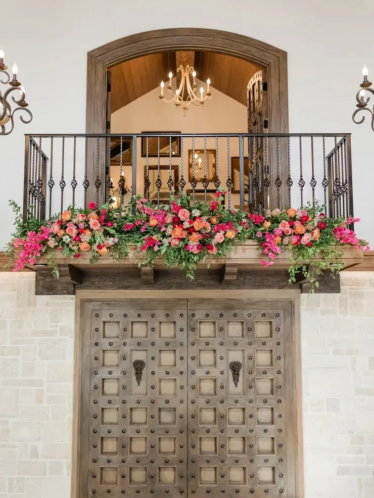 Carved wood doors and iron balcony railing with floral arrangement at 9 Aviles wedding venue