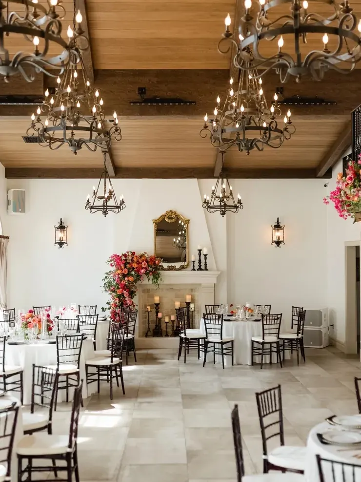 Vaulted wood-beam ceiling and iron chandeliers over reception tables at 9 Aviles