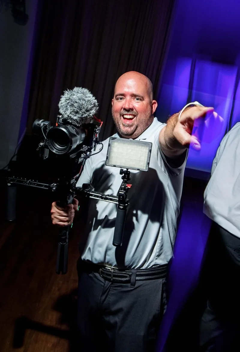 Austin of Coastal Creations Video filming a wedding reception with a gimbal-mounted camera, shotgun microphone and LED light