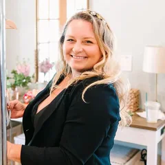 Brittany Alphonso of Honey Bee Events, smiling beside a rack of wedding and bridesmaid dresses