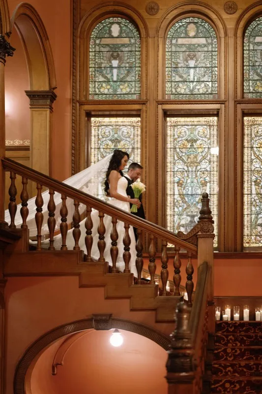 Bride and groom on the staircase under Tiffany stained glass windows at Flagler College