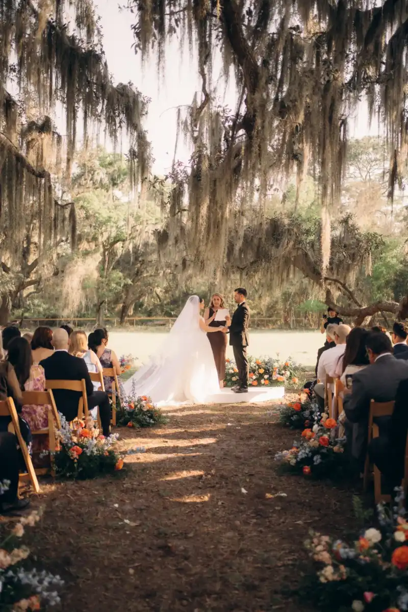 Bride in a cathedral veil and groom exchanging vows on a low white platform in the open pasture at Golden Creek Ranch