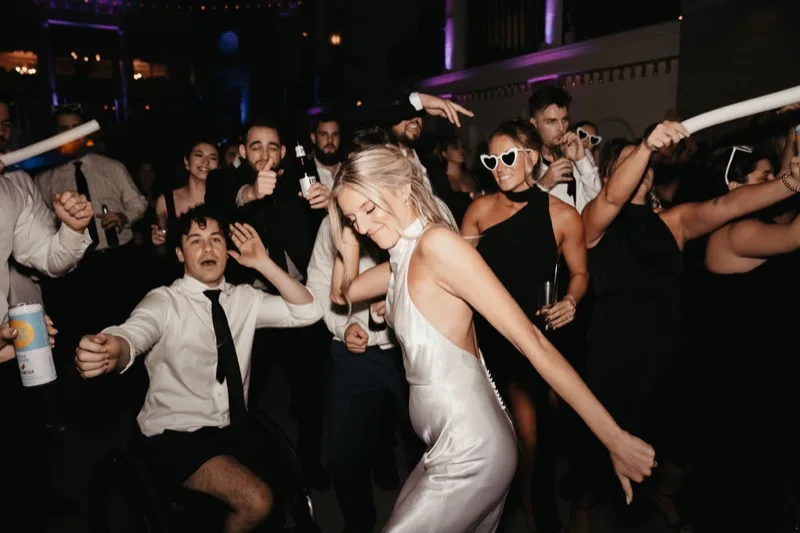Packed dance floor at Lightner Museum wedding with purple uplighting