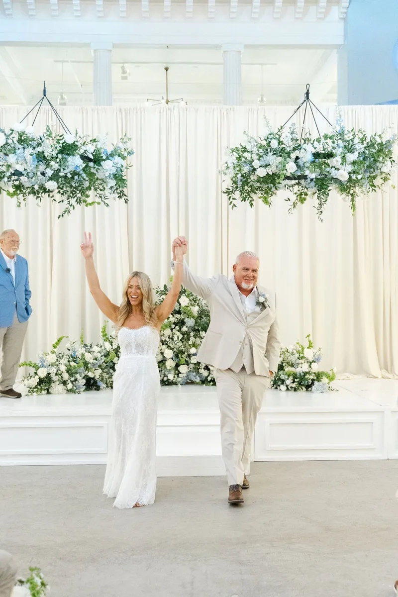 Just-married couple raising hands during ceremony recessional at Lightner Museum