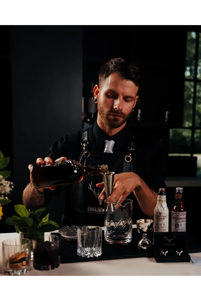A McKarls bartender pouring bourbon into a jigger while building a craft cocktail
