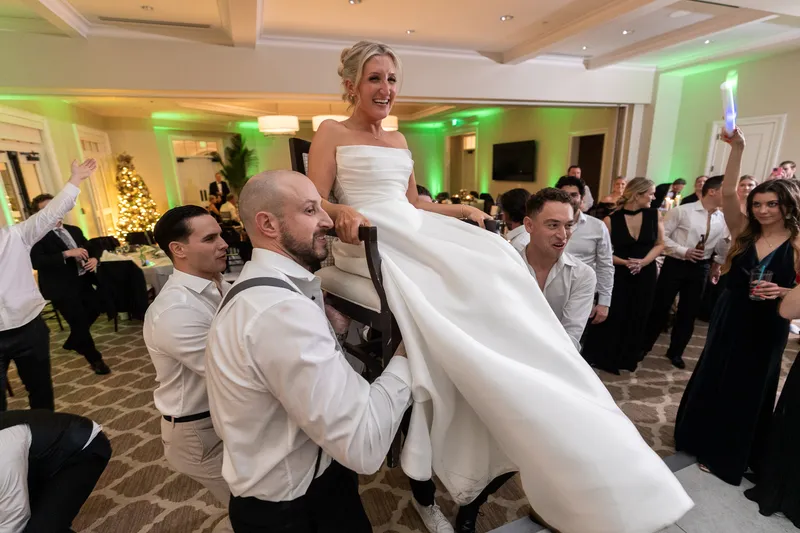 Bride lifted on chair during hora at Sawgrass Country Club wedding reception