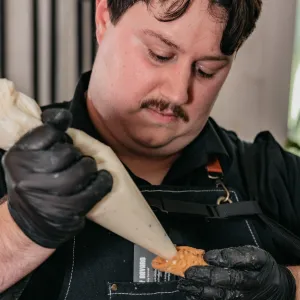 Anthony of That Cannoli Guy piping filling into a cannoli shell