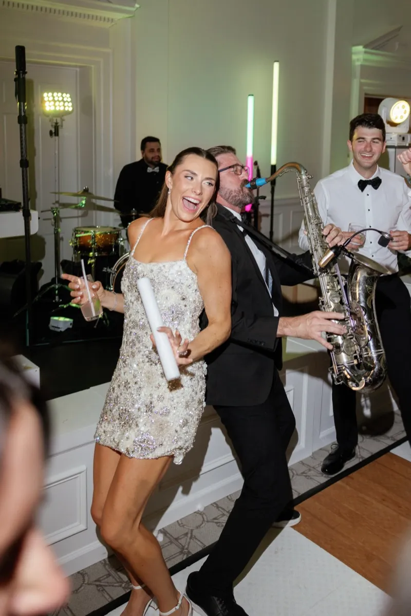 Bride and COS Celebrations saxophonist Corey Peterson leaning back to back on the Timuquana Country Club dance floor while he plays tenor sax