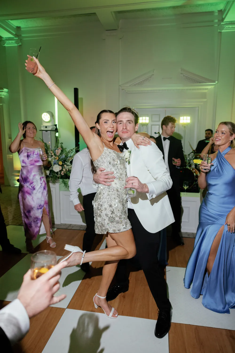 Bride and groom celebrating on the Timuquana Country Club dance floor with green uplighting and guests around them