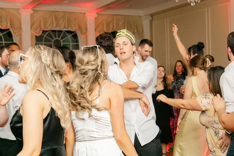Packed wedding dance floor at Timuquana Country Club in Jacksonville with the ballroom walls and columns washed in warm coral uplighting