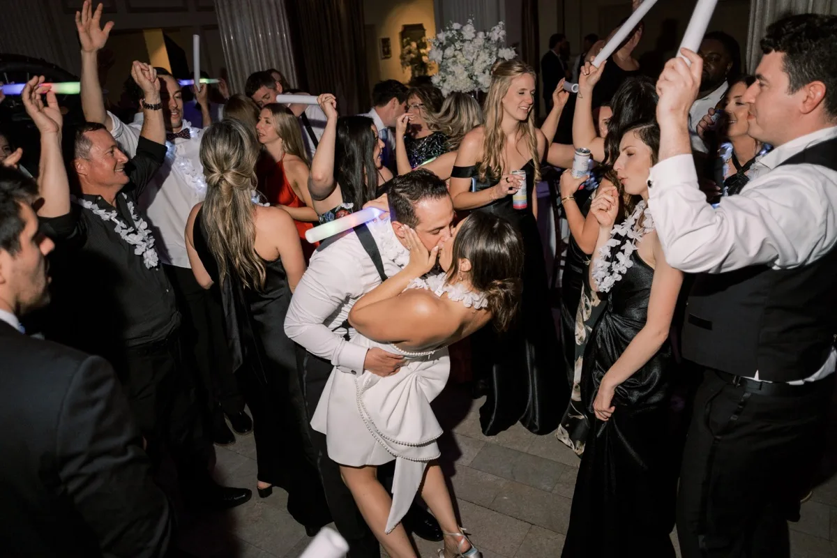 Bride and groom dip kiss on packed dance floor with glow sticks at Treasury on the Plaza wedding